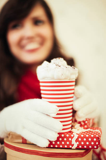 Young woman holding hot chocolate and gifts 