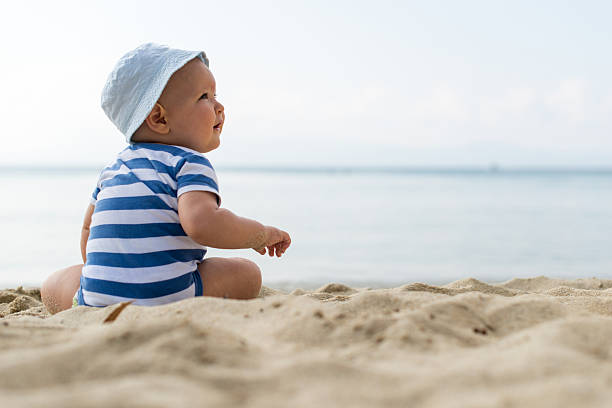 istock Baby boy with hat sitting on the beach 478649644