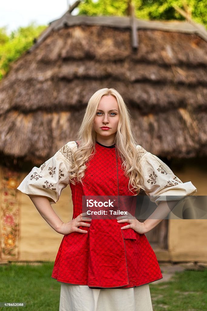 Young woman in red ukrainian national costume Young woman in red ukrainian national costume near old historic house 2015 Stock Photo