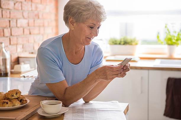 starszy kobieta za pomocą jej telefon komórkowy - retirement senior adult breakfast active seniors zdjęcia i obrazy z banku zdjęć