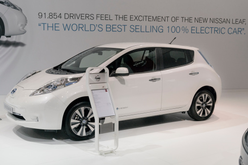Brussels, Belgium - January 14, 2014: White Nissan Leaf full electric car on display at the 2014 Brussels motor show. People in the background are looking at the cars.