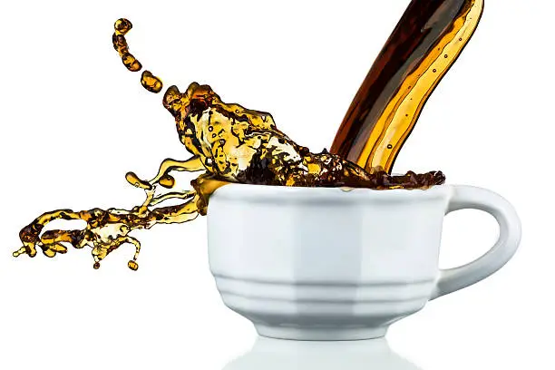 Hot Coffee Pouring, Spilling, Isolated on White, Freeze-Frame.  This image is a real shot of spilling coffee shot with a super fast exposure to perfectly freeze the motion.