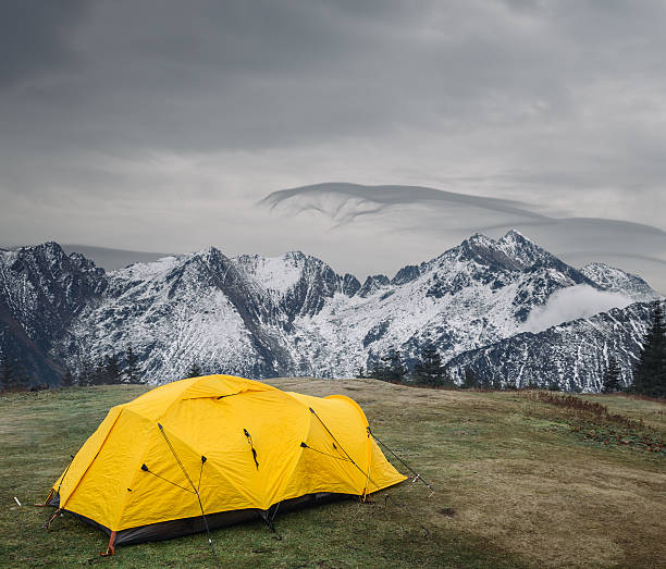 bright yellow camping tent in front of the mountains