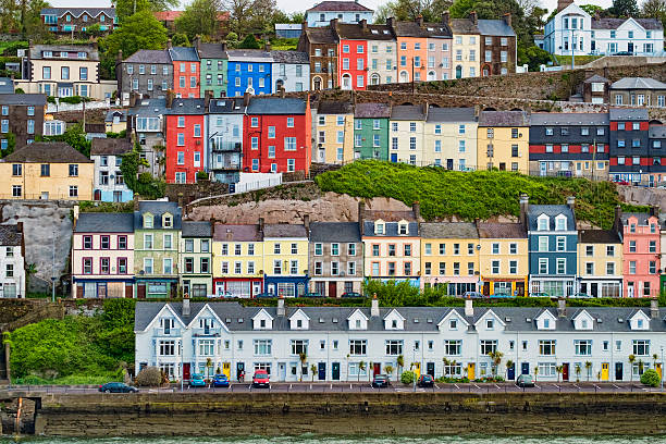 Colourful Houses in Cobh, Ireland Horizontal image of Cobh, Ireland with colourful houses in rows on the hillside in town.  Houses can be seen in the bottom of the image at sea level and then proceeding up the hill to the top.  These are townhouses that are all attached in rows and are brightly coloured as well. The second from the bottom row of house are along the residential part of the Cobh high street.  Image taken in late summer from sea level. county cork stock pictures, royalty-free photos & images