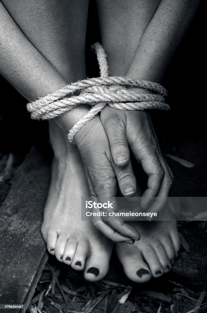 Human trafficking - Concept Photo Missing kidnapped, abused, hostage, victim woman with hands and legs tied up with rope in emotional stress and pain, afraid, restricted, trapped, struggle, terrified, threaten, locked in a cage cell. Human Trafficking Stock Photo