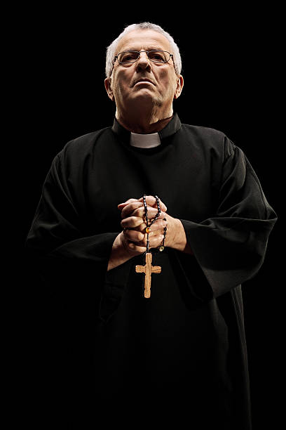 Catholic reverend holding a wooden cross Catholic reverend holding a wooden cross isolated on black background priest photos stock pictures, royalty-free photos & images