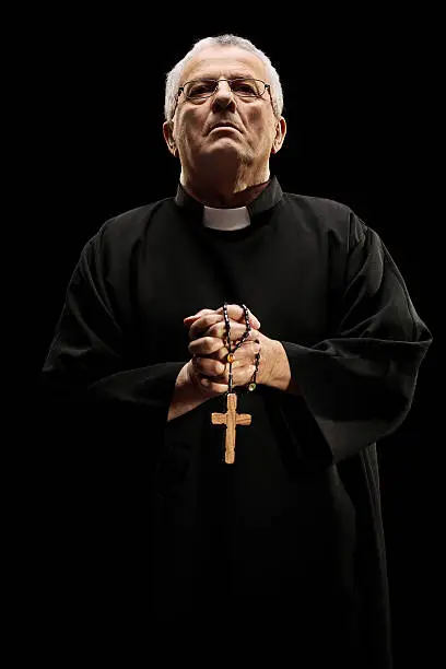 Catholic reverend holding a wooden cross isolated on black background