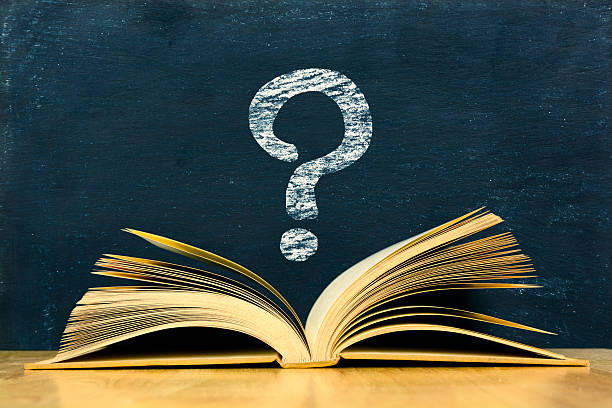 Question mark symbol above vintage old book on blackboard background stock photo