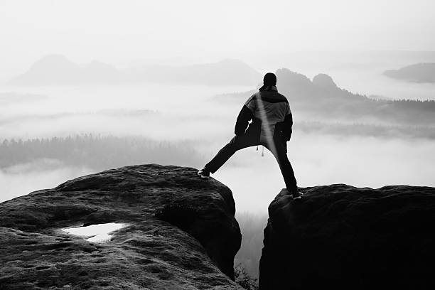 istock Hiker in black is jumping between the rocky peaks. 478667378
