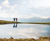 Trekkers passing by a calm lake in the mountains