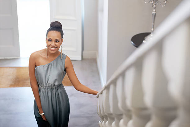 She's a vision Portrait of an attractive young woman smiling while standing on a staircase black woman hair bun stock pictures, royalty-free photos & images