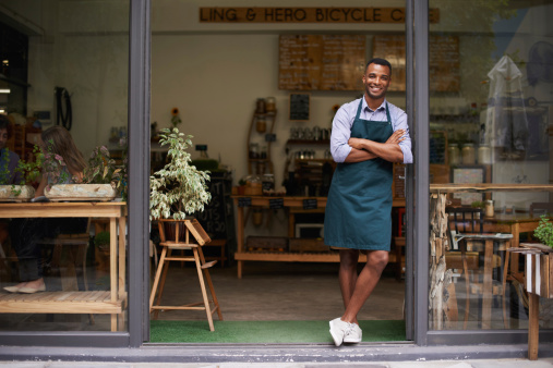 A handsome young man standing in the entrance to his store