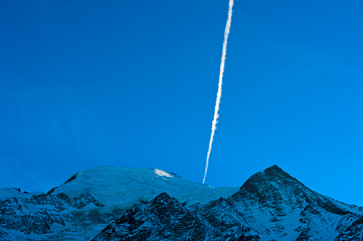 Contrail of an airplane over a snowy mountain peak, Chamonix, Haute-Savoie, France