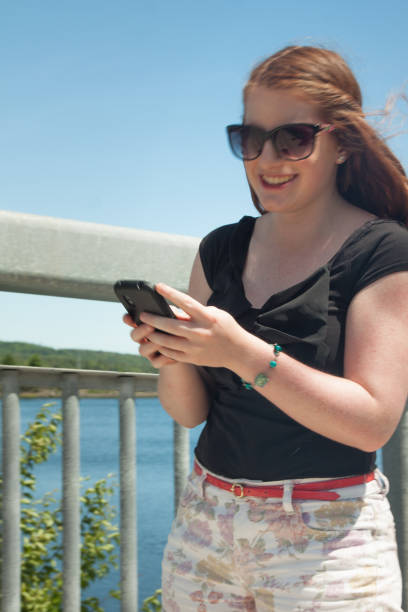 istock Girl with sunglasses using smartphone outdoors 478672170