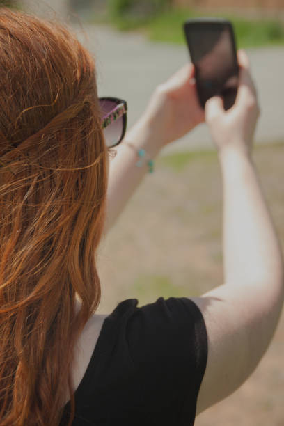 istock back view of a redhaired woman taking a selfie 478672228