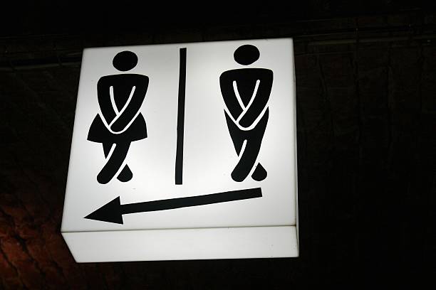 humorvolle hinweisschild männliche und weibliche toiletten - überkreuzte beine stock-fotos und bilder