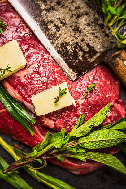 Raw beef meat with butter, old cleaver and fresh herbs