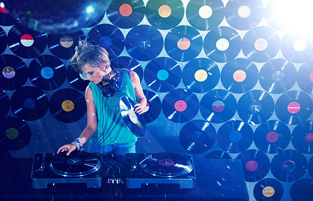 Portrait of a trendy young DJ standing behind her equipment busy changing records