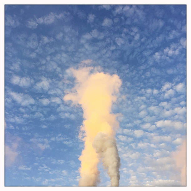 Smoke Stacks polluting a beautiful blue sky with smoke.  Photographed with an iPhone.
