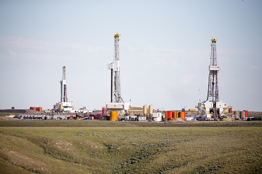 Three hydro-fracking derricks sitting on a plain.