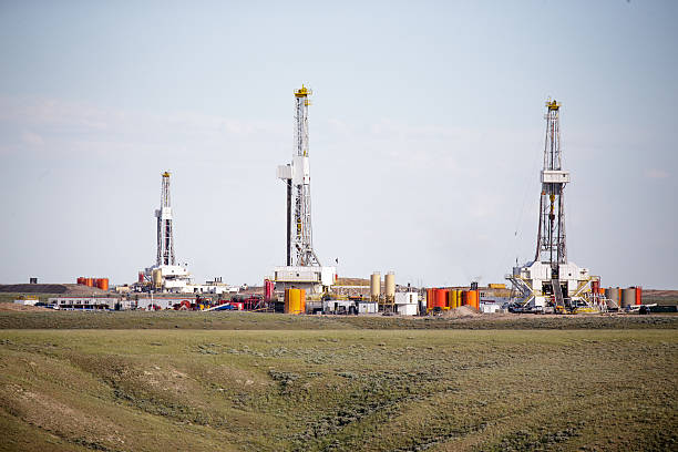 três hydro- fraturação hidráulica derricks de perfuração para um gás natural simples - fracking - fotografias e filmes do acervo