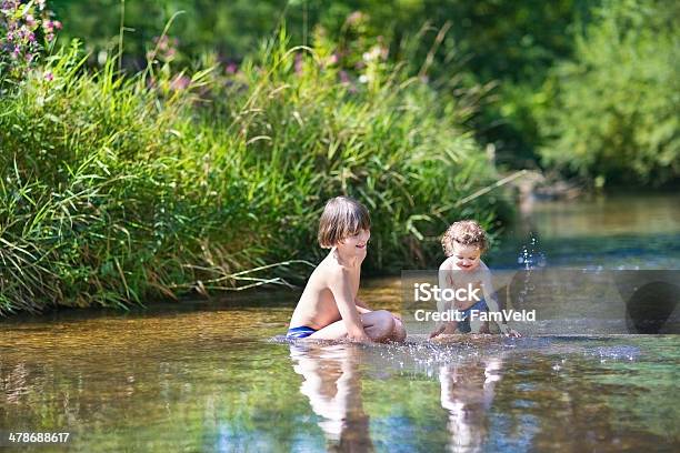 Young Cute Boy And His Baby Sister Playing In River Stock Photo - Download Image Now