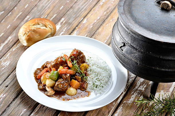 Traditional gourmet Stuffed Pickled Cabbage Sarma Rolls, cooked in spicy Tomato sauce with Smoked Pork Ribs chunks, served in large Stainless Steel Casserole with Serving Spoon, isolated on White Background, viewed directly above.