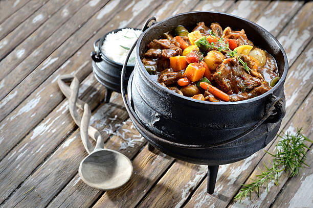 Traditional South African pot stew or potjiekos in the three-legged pot used to cook this dish on an open fire. Usually served with rice dished with a large spoon.