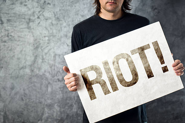 istock RIOT. Man holding poster with printed protest message 478690079