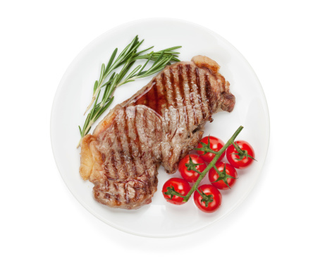 Sirloin steak with rosemary and cherry tomatoes on a plate. Isolated on white background