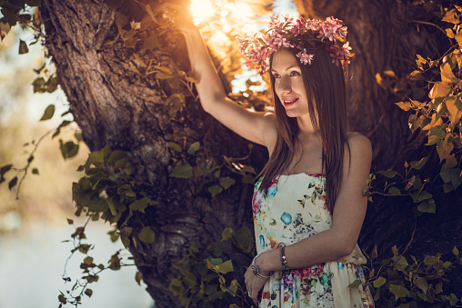 Young beautiful woman posing with flower crown on her head during spring day.
