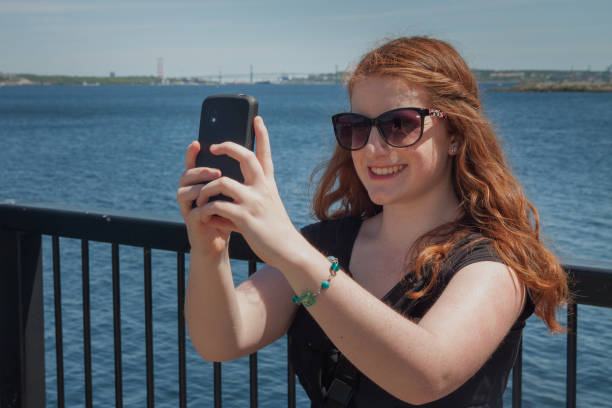 istock redhaired woman in sunglasses taking a selfie on a bridge 478703668