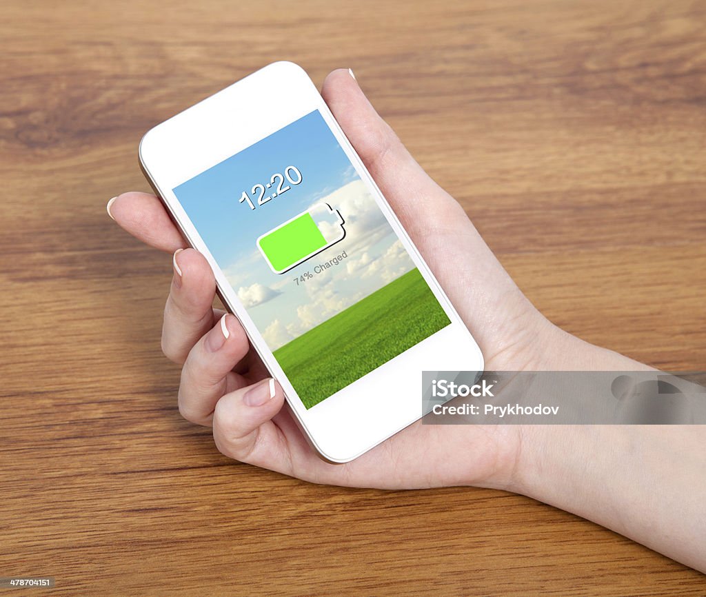 Donna mano tiene un telefono touch bianco con batteria - Foto stock royalty-free di Adulto