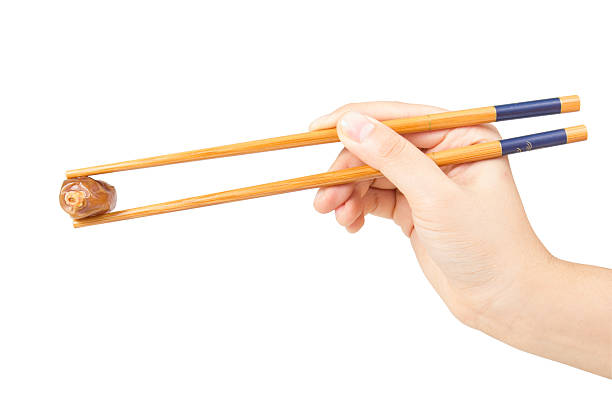 istock Chopstick holding by hand keeping dates fruit isolated on white 478704440