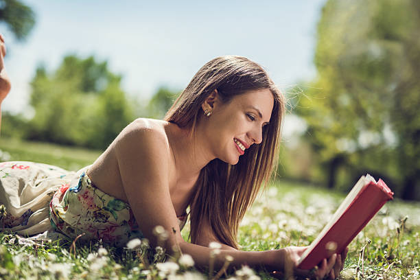 istock Smiling female student enjoying outdoors and learning from a boo 478707234