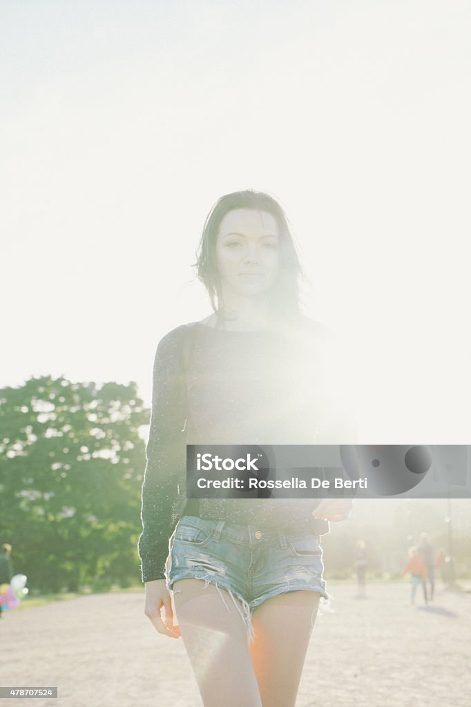 Cheerful Young Woman Walking Down Pathway In A Park Cheerful young woman walking down pathway in a park. Bright Stock Photo