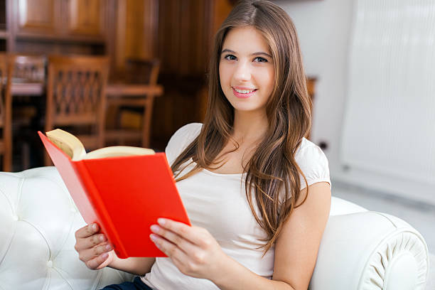 istock Woman reading a book while relaxing on the couch 478710760