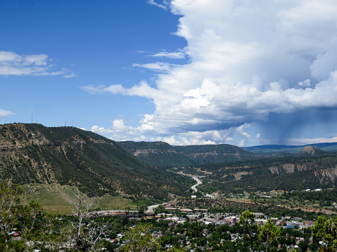 Storm clouds with rain is moving in on the idyllic mountain town of Durango, Colorado.  The image shows the rolling hills around the small town and buildings in the center of the city.