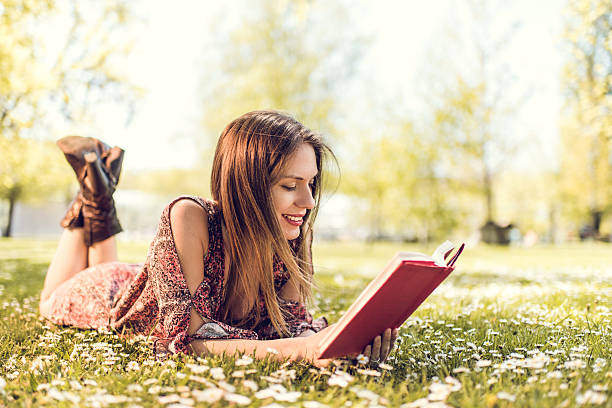 istock Smiling woman relaxing in grass and reading a book. 478724820