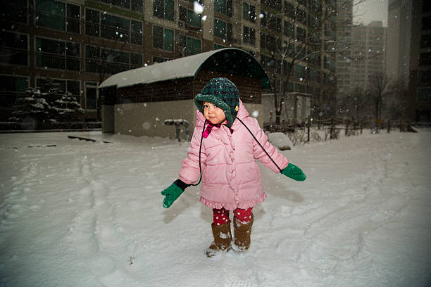 12) Shot of a cute asian baby playing in the snow at a playground.