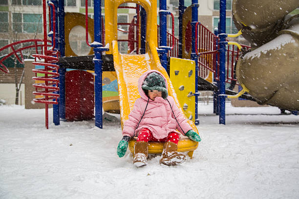 21) Shot of a cute asian baby playing in the snow at a playground.