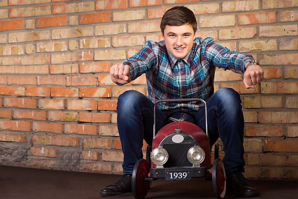 Young Man Riding on Vintage Toy Car