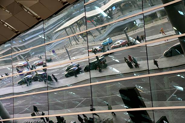 Shenzhen Bao'an International Airport, terminal glass facade. Passengers are reflected walking through the building. 