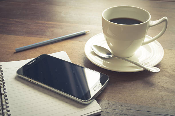 Smart phone with coffee cup,book and pencil.