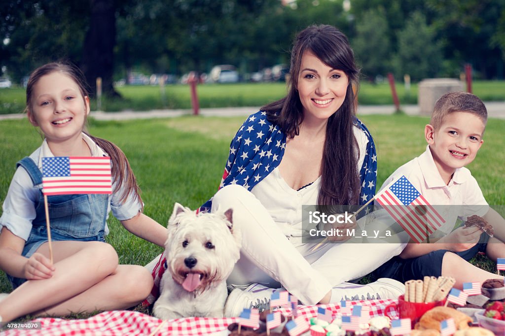 Fourth of July family picnic. Mother with cute children and dog enjoying July 4th picnic. Fourth of July Stock Photo