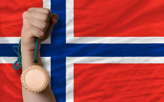 Holding bronze medal for sport and national flag of norway
