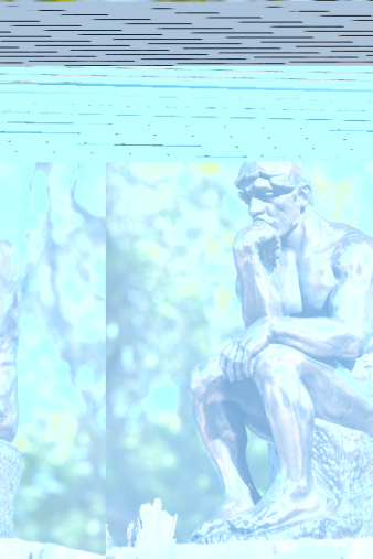 View of a small bronze replica of Rodin's The Thinker statue, sitting in a spot of light in a forest.  The Thinker is often used to represent philiosphy.