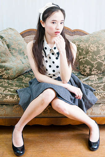 Young attractive lady looking at camera while sitting on vintage sofa