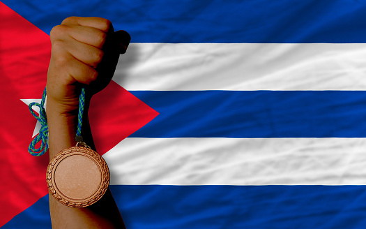 Holding bronze medal for sport and national flag of cuba