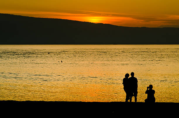 Three People in silhouette at Beach stock photo